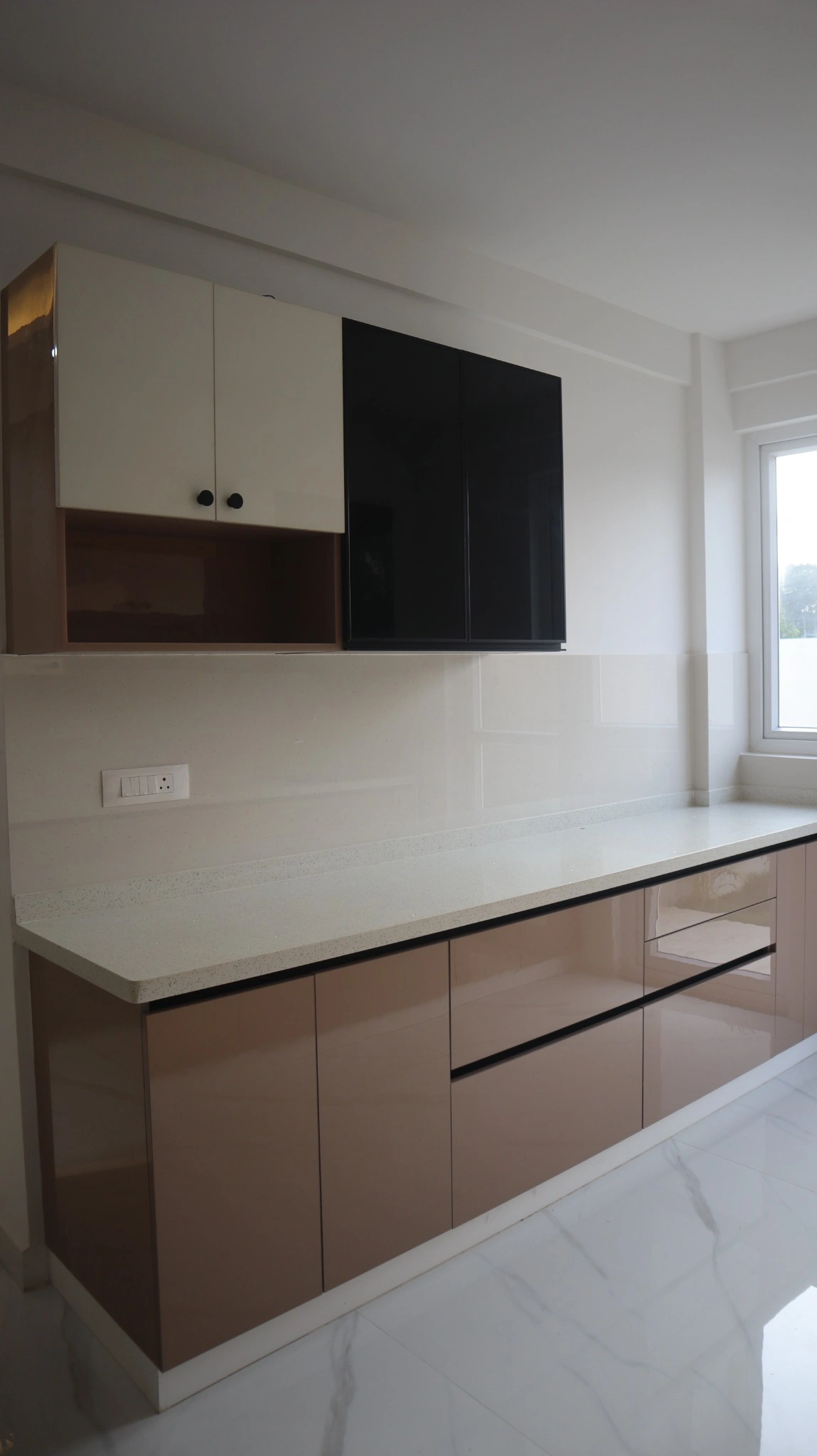 Handle-less modular kitchen with glossy champagne base units and quartz counter