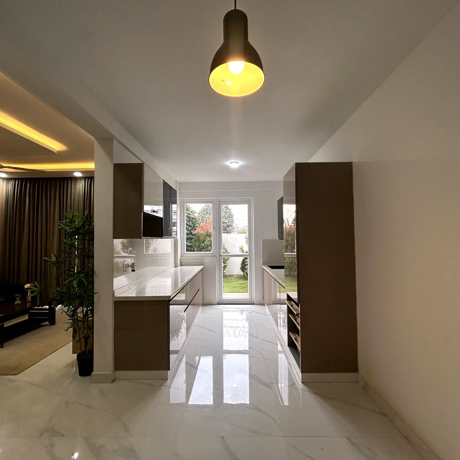 Parallel modular kitchen with warm wood-tone tall units and marble-look flooring