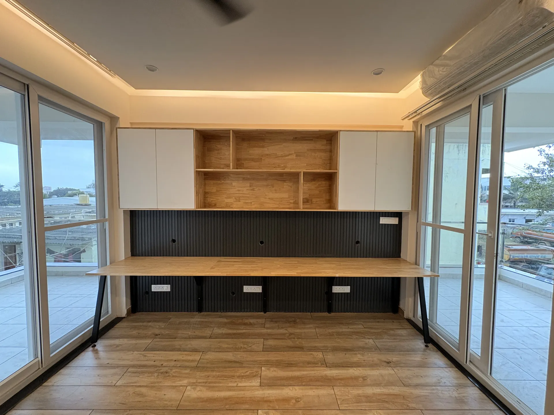 Study nook with a long wood-laminate desk and wall cabinets over a charcoal fluted panel, villa at SVS Silver Oaks, Heelalige