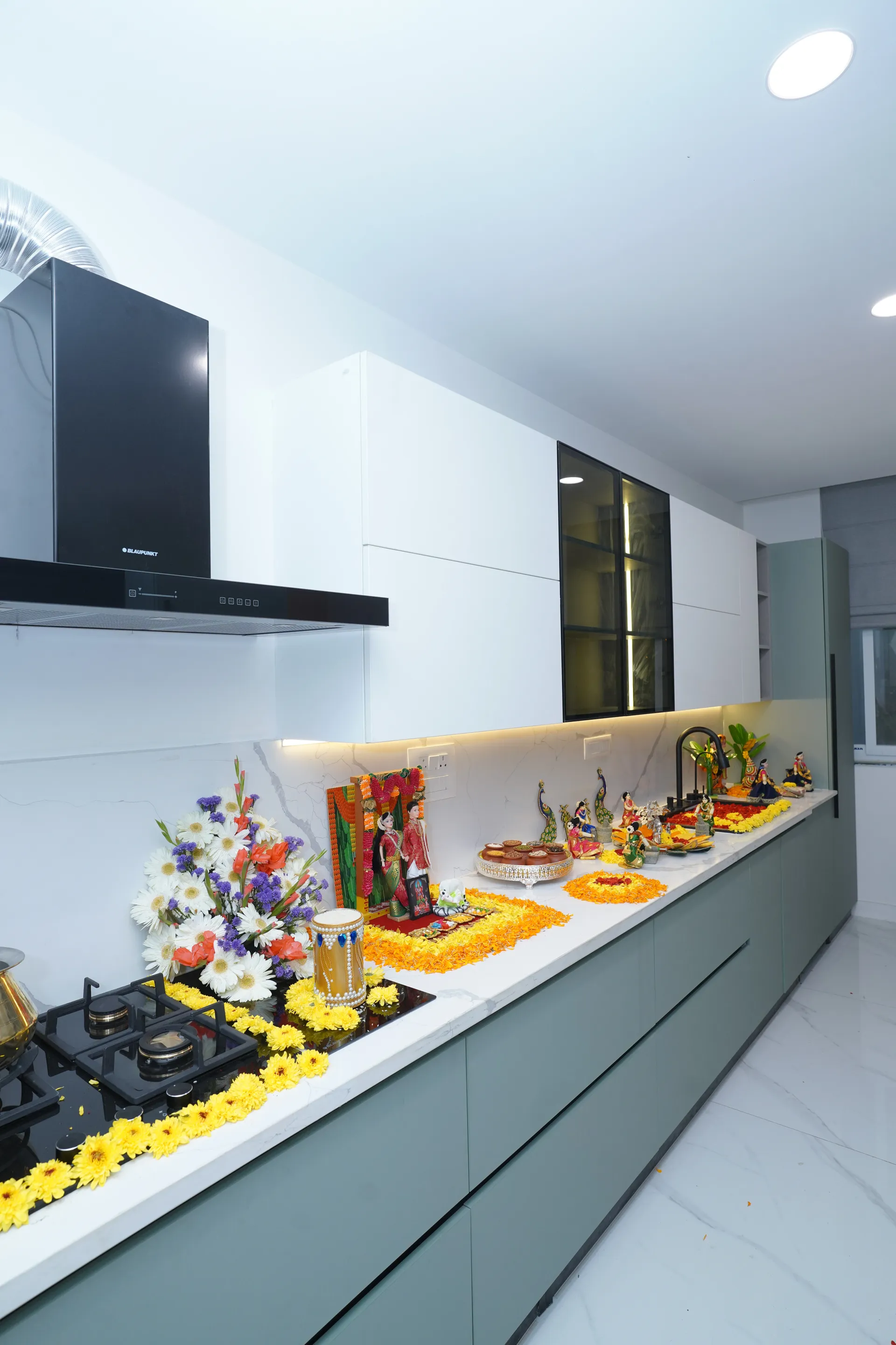 Sage-green modular kitchen with black hob, chimney and glass-front overhead cabinet, villa at SVS Silver Oaks, Heelalige
