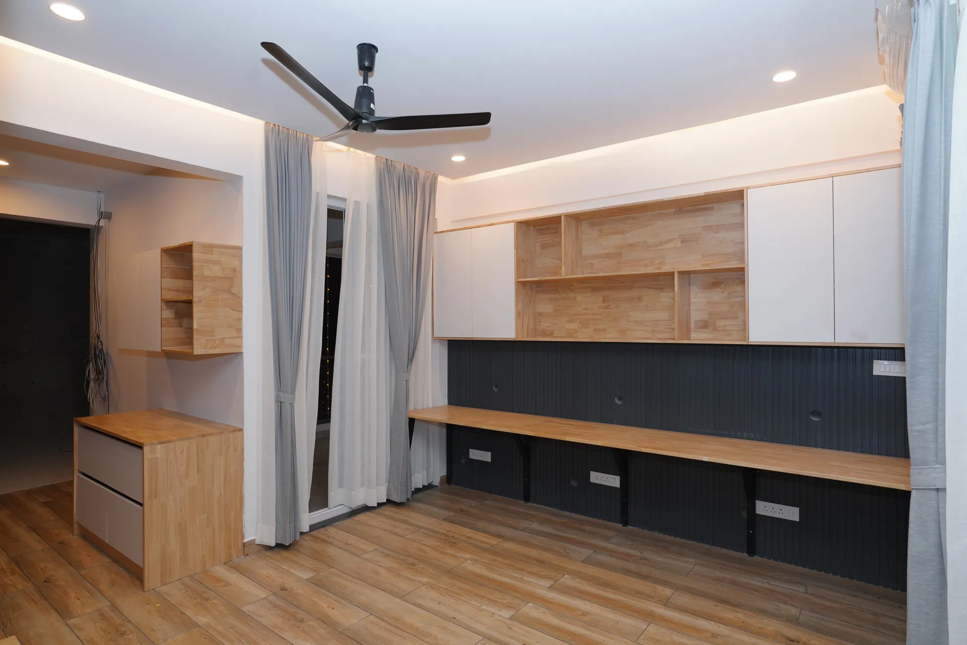 Long study desk with wall storage in wood laminate over a charcoal fluted back panel, villa at SVS Silver Oaks, Heelalige