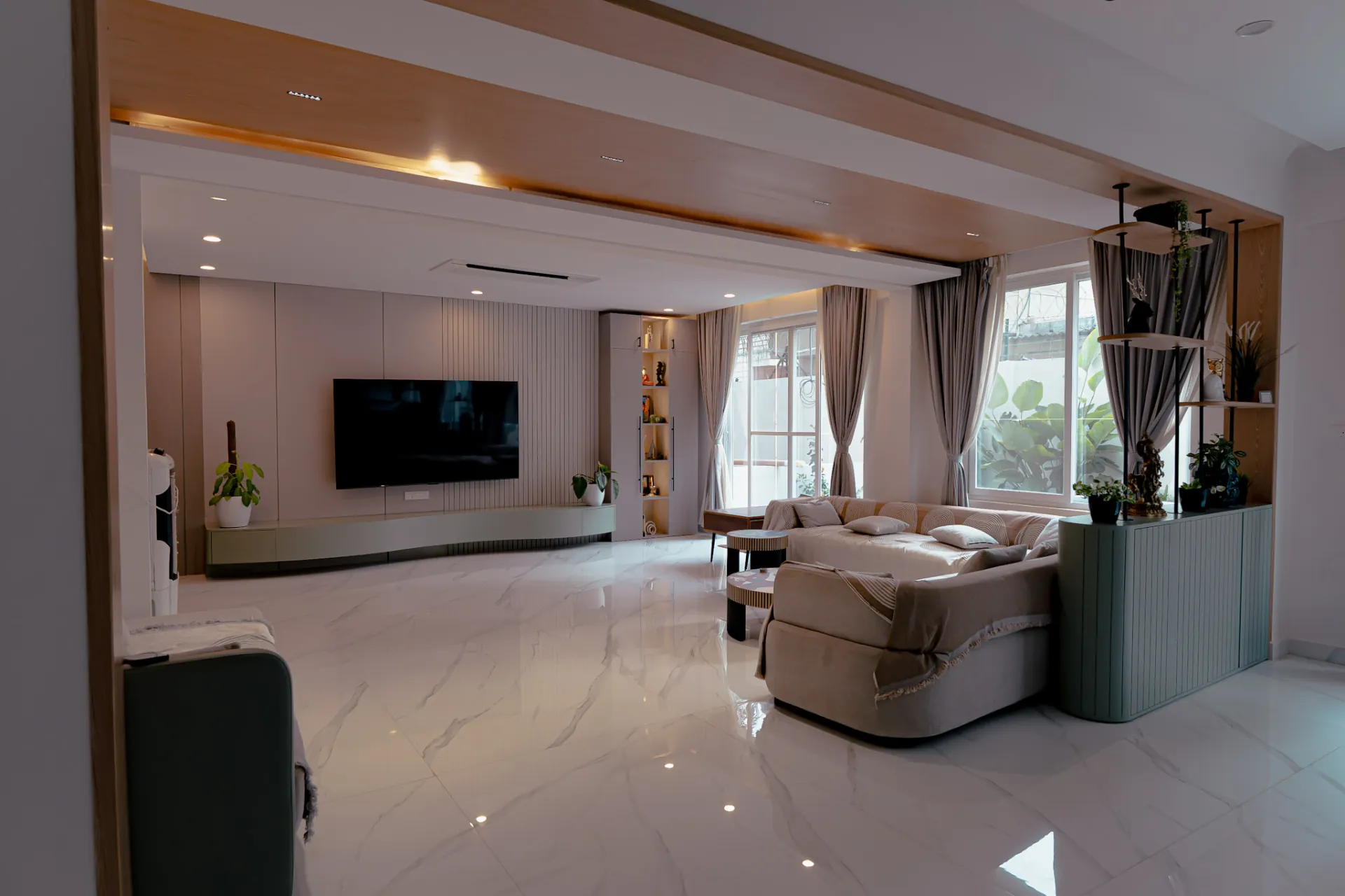 Open living room with a wood-trimmed ceiling, the curved sage TV unit on the far wall and a sage fluted partition with display shelves, villa at SVS Silver Oaks, Heelalige
